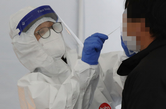 낮 기온이 영하 7도에 머무는 등 세밑 한파가 찾아온 30일 청주시 흥덕보건소 선별진료소에서 의료진이 검사를 받으러 온 시민의 검체를 채취하고 있다.  연합뉴스